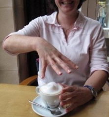 Die Hand zeichnet mit allen Fingern.... Für Capuccino zeichnet die Hand mit allen Fingern eine Schaumkrone nach